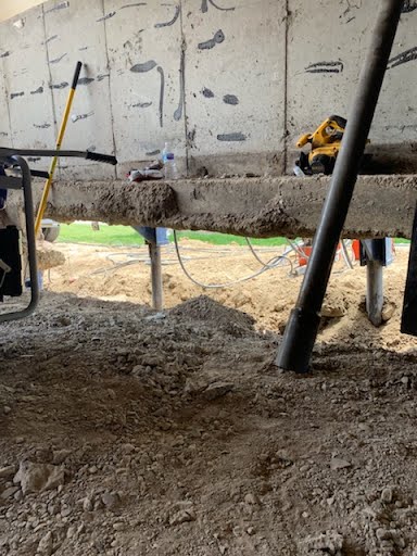 Piers installed beneath a raised garage slab during a foundation lift