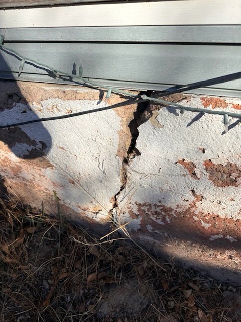 Vertical crack in a concrete foundation wall beneath exterior siding