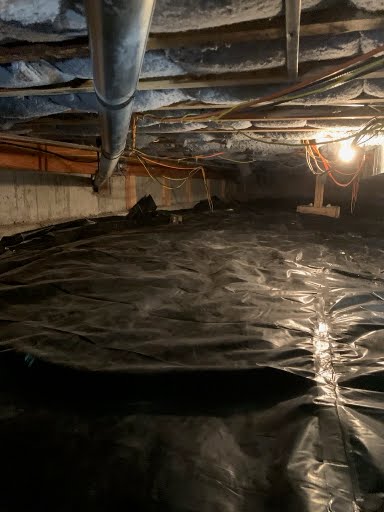 Sealed vapor barrier covering the dirt floor of a crawl space after drainage work