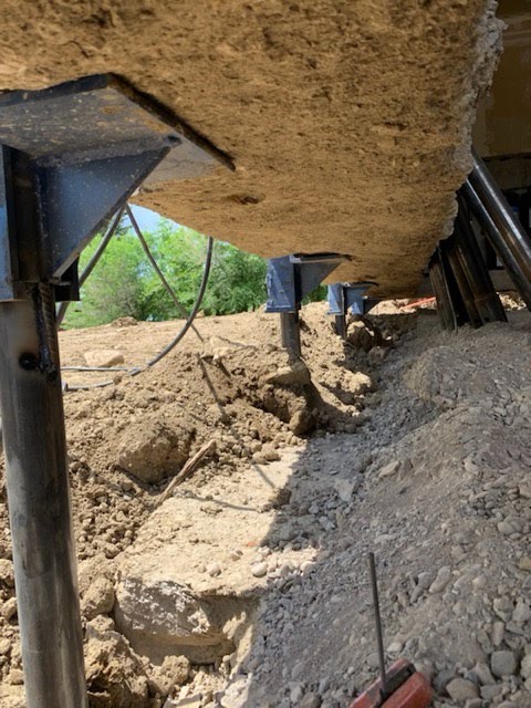 Steel push piers with lifting brackets supporting an exterior foundation wall