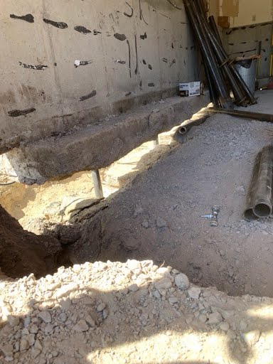 Excavated pier locations along a settling foundation wall during lifting work