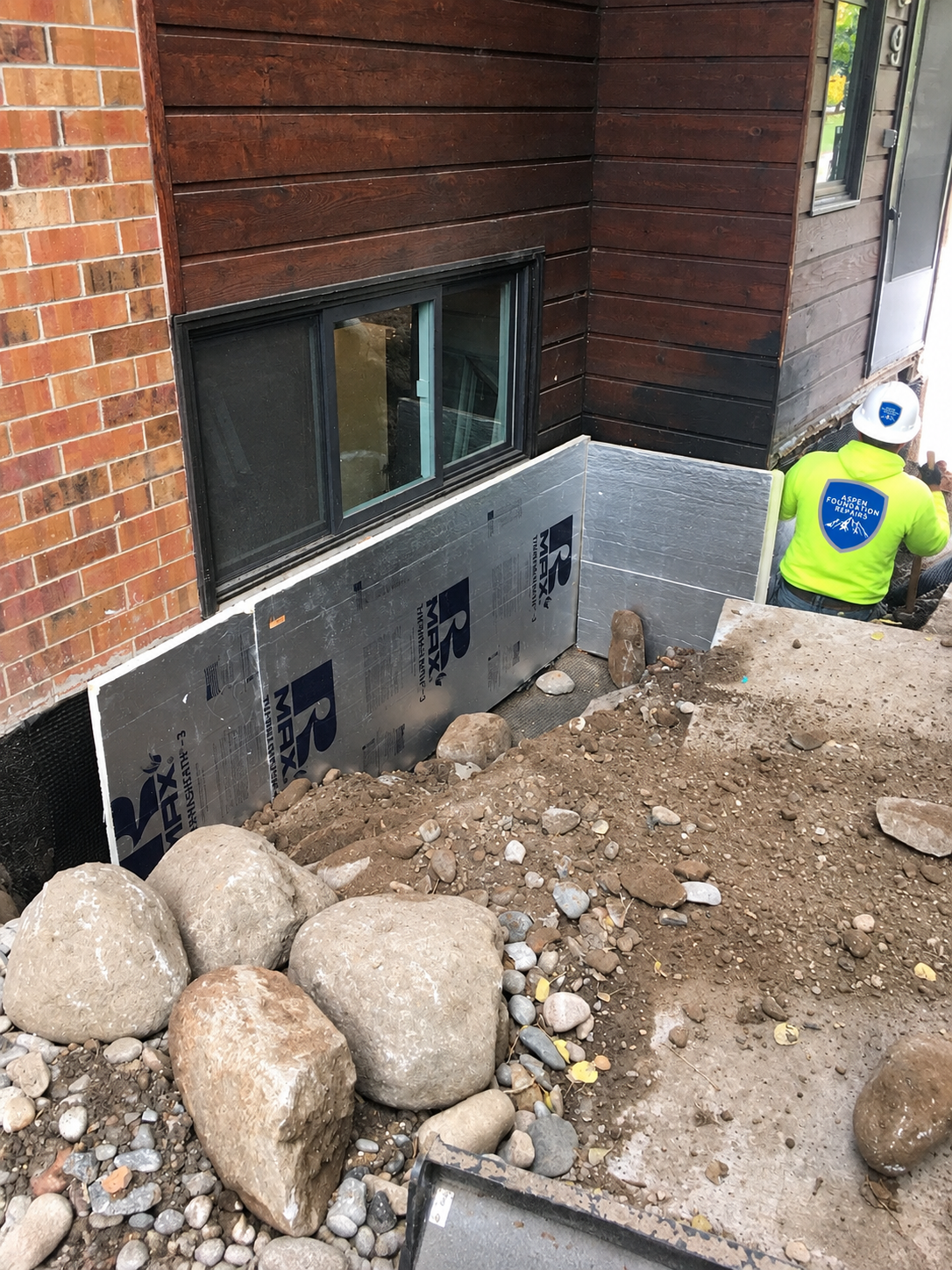 Rigid foam insulation board installed on a foundation wall below a basement window