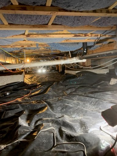 Finished crawl space with vapor barrier, drainage piping, and insulated floor joists