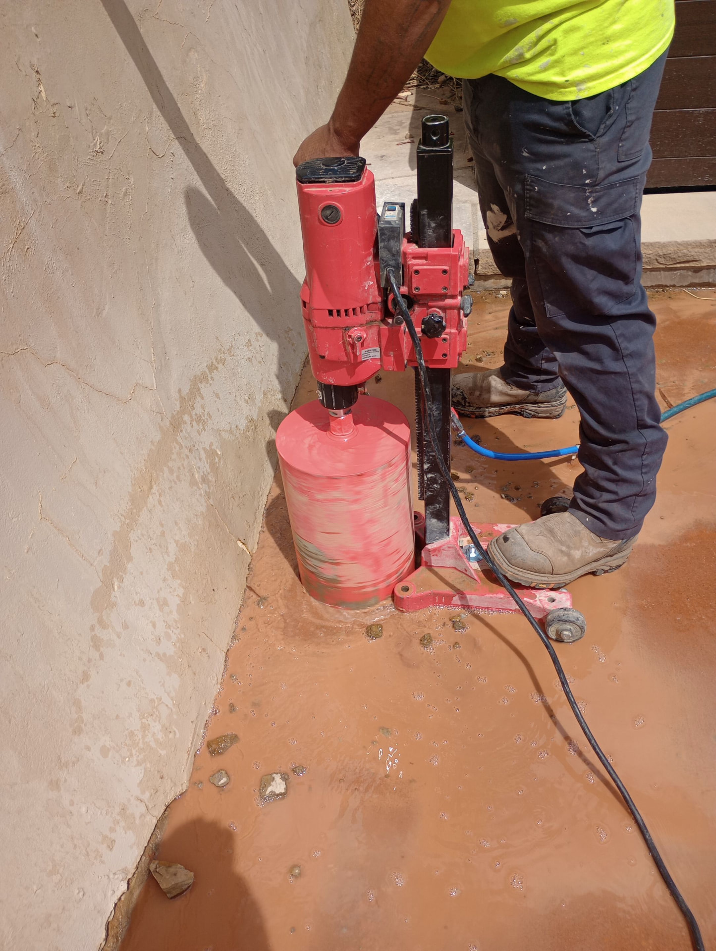 Core drilling a drain penetration at the base of a retaining wall