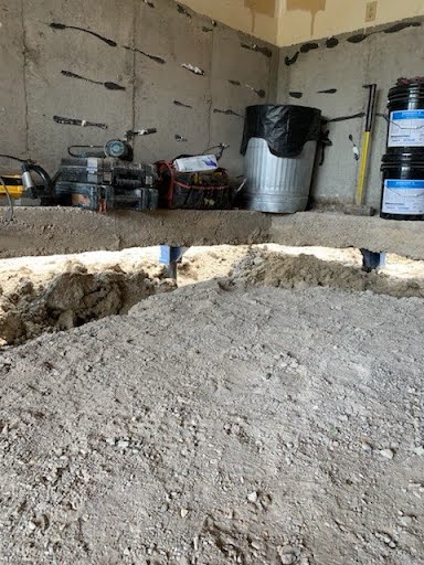 Garage slab staged for foundation lifting with push pier locations marked along the wall