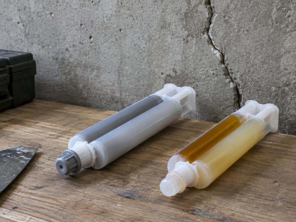 Epoxy and polyurethane injection cartridges beside a cracked wall