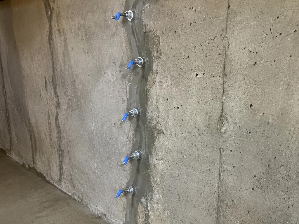 Injection ports set along a sealed basement wall crack