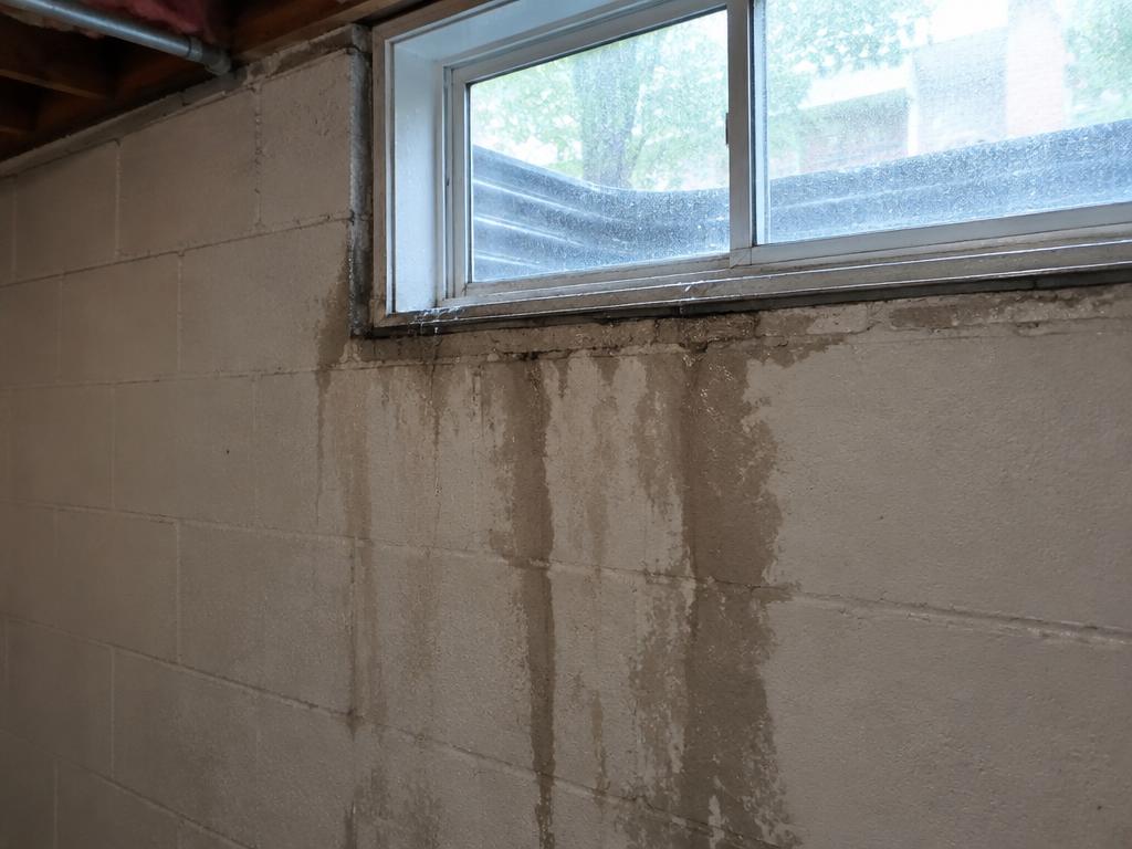 Water staining running down a basement wall below a leaking window